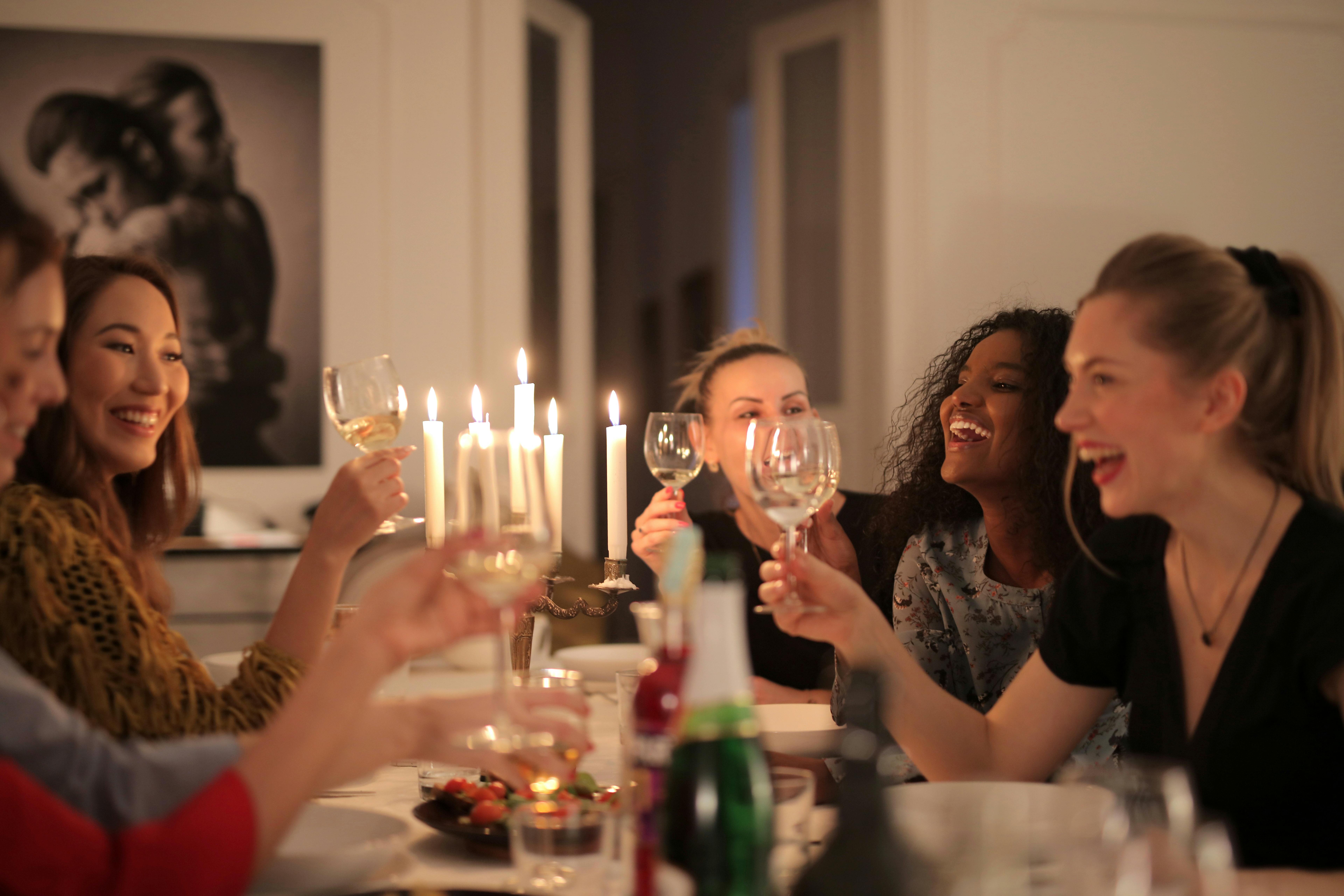 Friends laughing and toasting at a candlelit supper club dinner